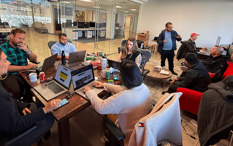 Punch Team Culture Photo-10 A diverse group of people working and discussing around a table in a modern office space.