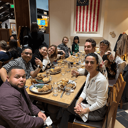 Punch Team Culture Photo 11 A group of diverse people enjoying a meal together at a restaurant with an American flag hanging on the wall.