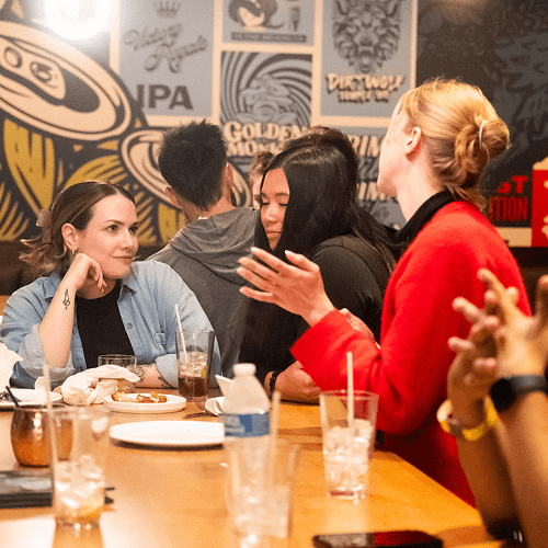 Punch Team Culture Photo 12 Four women sit at a table in a lively restaurant, engaged in conversation with drinks and food in front of them.