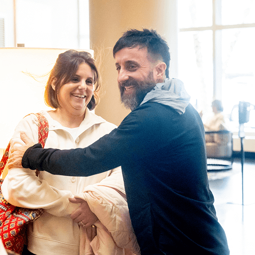 Punch Team Culture Photo 2 A man and woman smile and shake hands warmly in a bright indoor space.