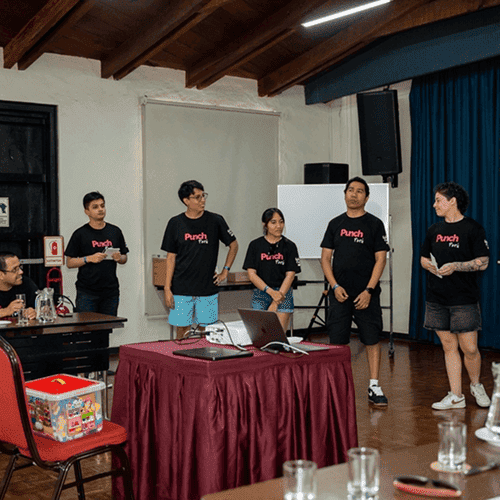 Punch Team Culture Photo 21 Five people stand in a room with a whiteboard, wearing matching "Punch" t-shirts, possibly giving a presentation or