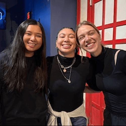 Punch Team Culture Photo 6 Three women smiling together indoors, with a blue wall and red window frame in the background.