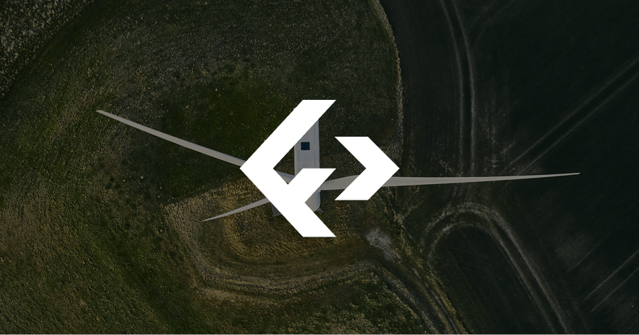 A drone captures an aerial view of a wind turbine with a large white logo overlay in the center, surrounded by green fields